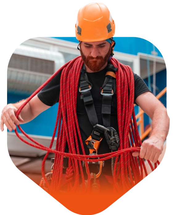 Homme avec un harnais de sécurité, un casque de chantier et une corde rouge